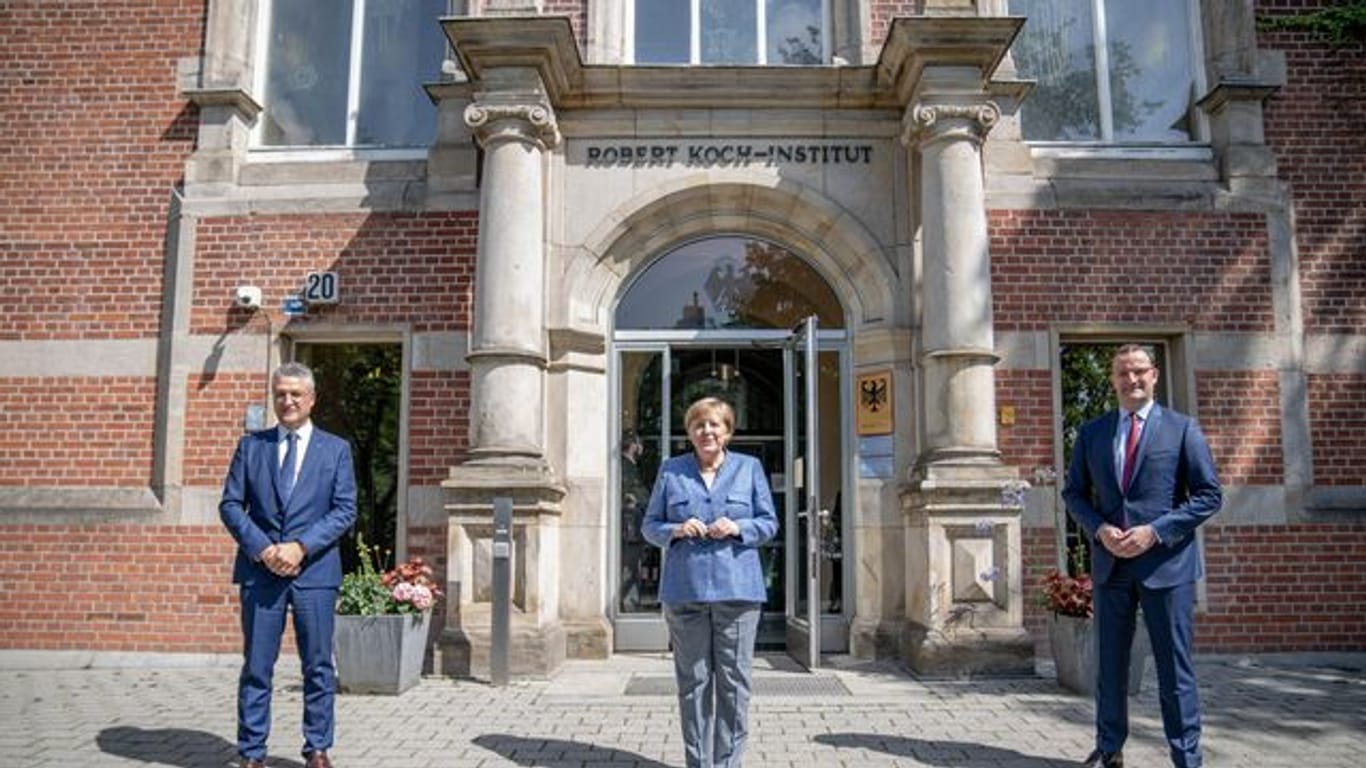 RKI-Präsident Lothar Wieler, Bundeskanzlerin Angela Merkel und Bundesgesundheitsminister Jens Spahn vor dem Eingang zum Robert Koch-Institut.