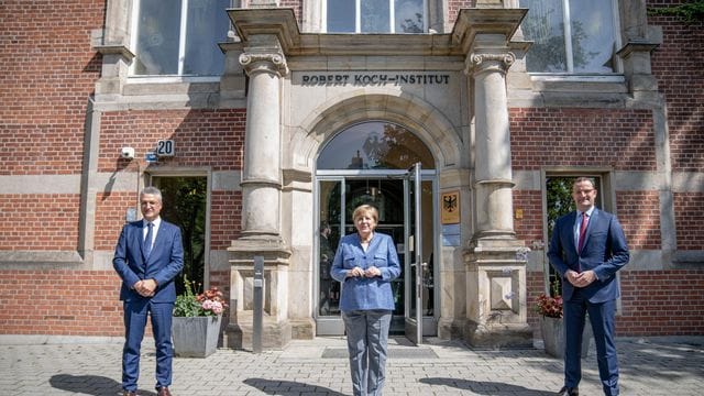 RKI-Präsident Lothar Wieler, Bundeskanzlerin Angela Merkel und Bundesgesundheitsminister Jens Spahn vor dem Eingang zum Robert Koch-Institut.