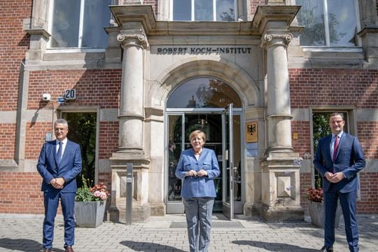 RKI-Präsident Lothar Wieler, Bundeskanzlerin Angela Merkel und Bundesgesundheitsminister Jens Spahn vor dem Eingang zum Robert Koch-Institut.