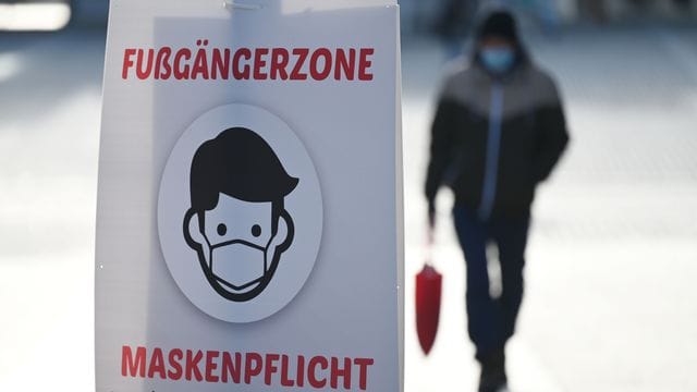 Ein Schild weist auf die Maskenpflicht in der Fußgängerzone hin.