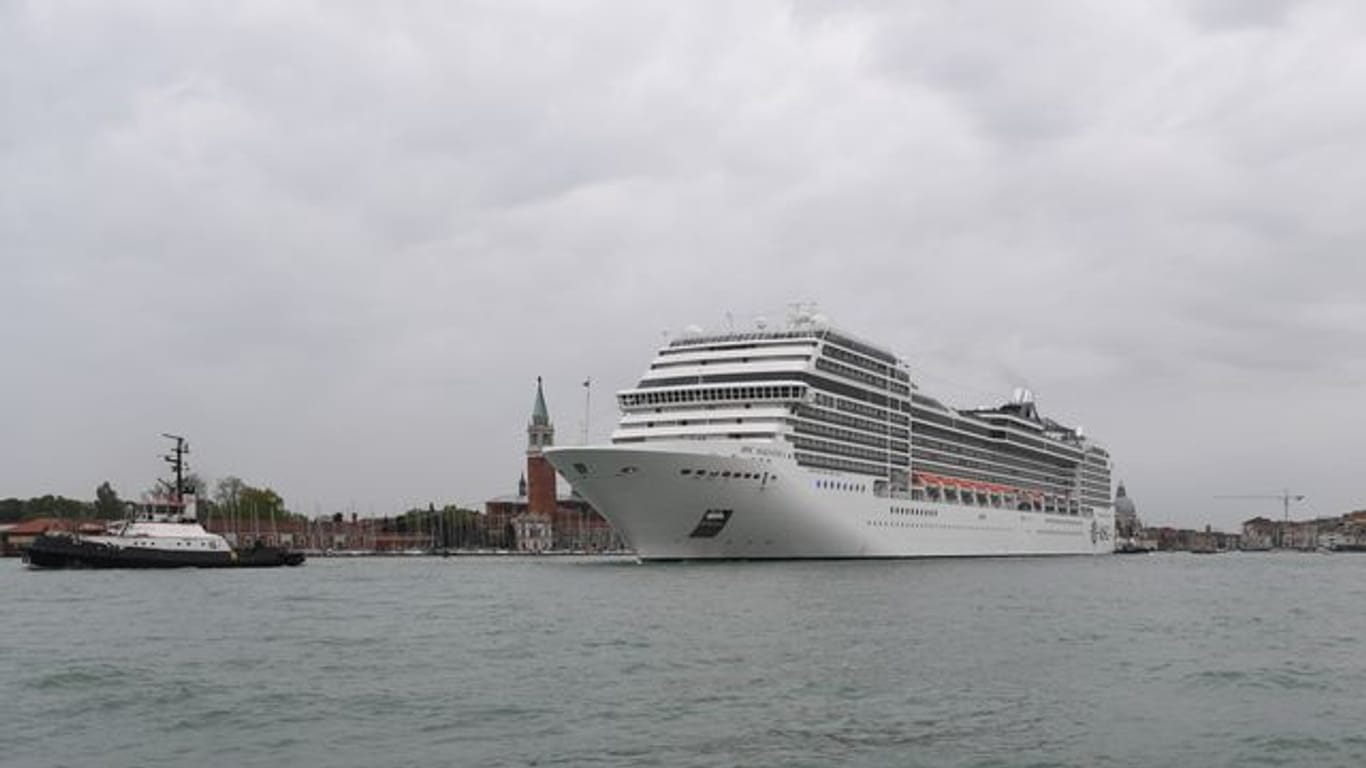 Ein Kreuzfahrtschiff fährt an der Lagunenstadt Venedig von einem Schlepper gezogen vorbei.
