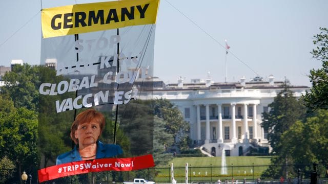 Ein Transparent vor dem Weißen Haus fordert Bundeskanzlerin Merkel dazu auf, ihre Ablehnung einer Sonderaussetzung für Impf-Patente aufzugeben.