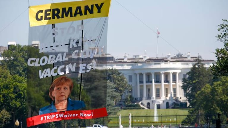 Ein Transparent vor dem Weißen Haus fordert Bundeskanzlerin Merkel dazu auf, ihre Ablehnung einer Sonderaussetzung für Impf-Patente aufzugeben.