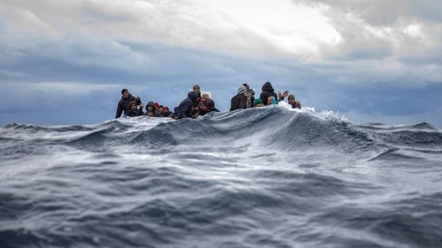 Männer aus Marokko und Bangladesch sitzen in einem überfüllten Holzboot im Mittelmeer vor der Küste von Libyen. Männer aus Marokko und Bangladesch sitzen in einem überfüllten Holzboot im Mittelmeer vor der Küste von Libyen.