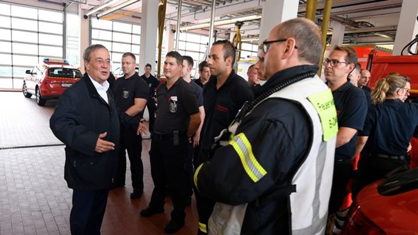 Der nordrhein-westfälische Ministerpräsident Armin Laschet (CDU, l) bedankt sich bei Hagenern Feuerwehrleuten für ihren Einsatz.