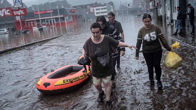 Anwohner in Lüttich waten mit einem Gummiboot durch das Wasser, nachdem die Maas bei schweren Überschwemmungen über die Ufer getreten ist.