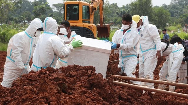 Arbeiter bereiten einen Sarg für eine Beerdigung auf dem speziellen Corona-Abschnitt eines Friedhofs in Indonesien vor.