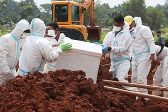 Arbeiter bereiten einen Sarg für eine Beerdigung auf dem speziellen Corona-Abschnitt eines Friedhofs in Indonesien vor.