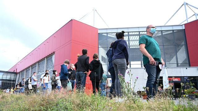 Menschen stehen vor dem Stadion des Fußball-Bundesligisten Mainz 05 Schlange für die Corona-Impfung. Menschen stehen vor dem Stadion des Fußball-Bundesligisten Mainz 05 Schlange für die Corona-Impfung.