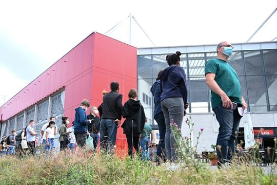 Menschen stehen vor dem Stadion des Fußball-Bundesligisten Mainz 05 Schlange für die Corona-Impfung.