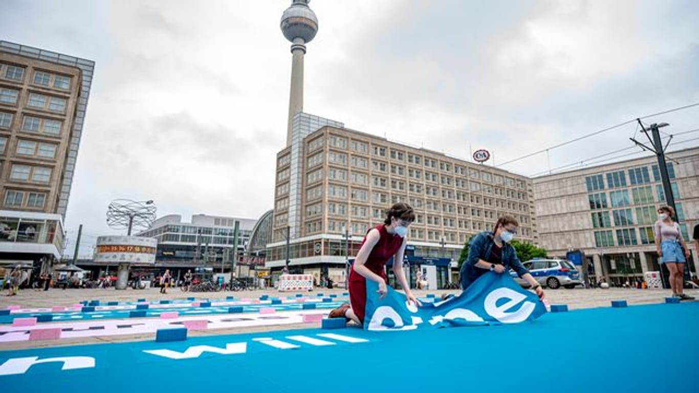 Greenpeace-Aktivisten legen auf dem Alexanderplatz einen 25 Meter großen Chatverlauf als Bodenbanner.