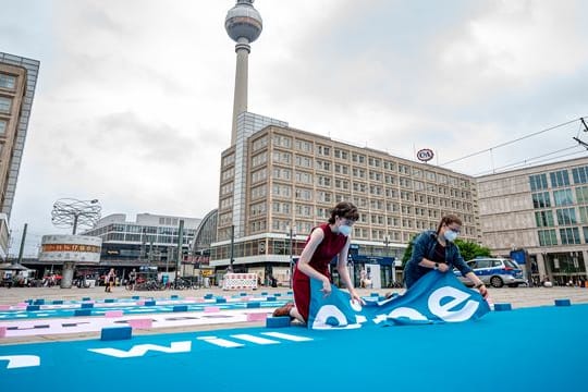 Greenpeace-Aktivisten legen auf dem Alexanderplatz einen 25 Meter großen Chatverlauf als Bodenbanner.