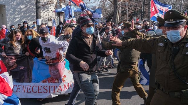 Unterstützer der kubanischen Regierung stoßen vor der kubanischen Botschaft auf Gegendemonstranten, die Plakate mit Bildern vom chilenischen Diktator Pinochet tragen.