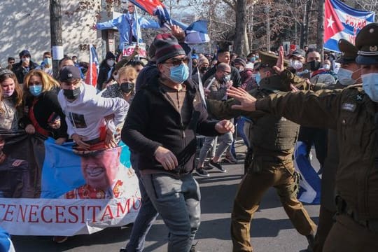 Unterstützer der kubanischen Regierung stoßen vor der kubanischen Botschaft auf Gegendemonstranten, die Plakate mit Bildern vom chilenischen Diktator Pinochet tragen.