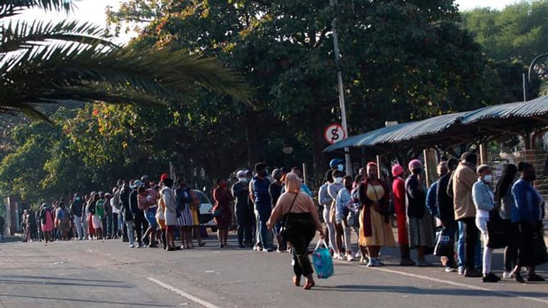 Menschen stehen in Durban vor einem Einkaufszentrum Schlange, um sich mit dem Nötigsten zu versorgen.