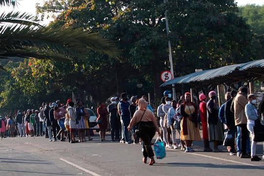 Menschen stehen in Durban vor einem Einkaufszentrum Schlange, um sich mit dem Nötigsten zu versorgen.