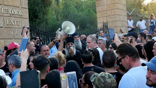 Ein griechisch-orthodoxer Priester spricht zu Demonstranten während des Protests gegen die Corona-Maßnahmen vor dem Präsidentenpalast. Ein griechisch-orthodoxer Priester spricht zu Demonstranten während des Protests gegen die Corona-Maßnahmen vor dem Präsidentenpalast.