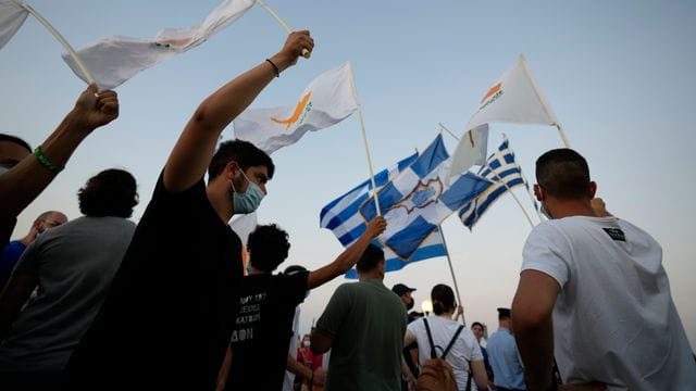 Bewohner der verlassenen Stadt Varosha oder Famagusta halten zypriotische und griechische Fahnen während eines Protestes gegen den türkischen Präsidenten Erdogan. Bewohner der verlassenen Stadt Varosha oder Famagusta halten zypriotische und griechische Fahnen während eines Protestes gegen den türkischen Präsidenten Erdogan.
