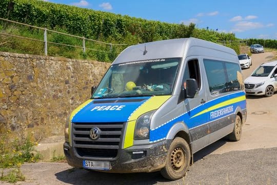 Ein Transporter mit der Aufschrift "Friedensfahrzeug" fährt am Rand des Katastrophengebiets in den Weinbergen entlang.