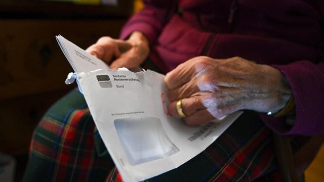 Eine Seniorin hält ihren Rentenbescheid in der Hand.