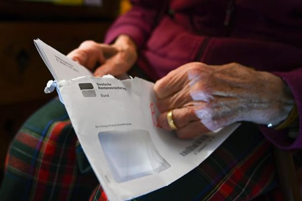 Eine Seniorin hält ihren Rentenbescheid in der Hand.