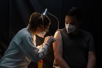 Eine Mitarbeiterin des Arbeiter-Samariter-Bundes (ASB) klebt nach einer Corona-Schutzimpfung ein Pflaster auf.