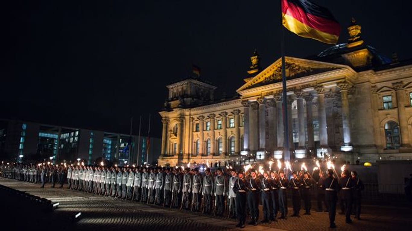 Zahlreiche Soldaten stehen bei einem Großen Zapfenstreich vor dem Reichstagsgebäude in Berlin.