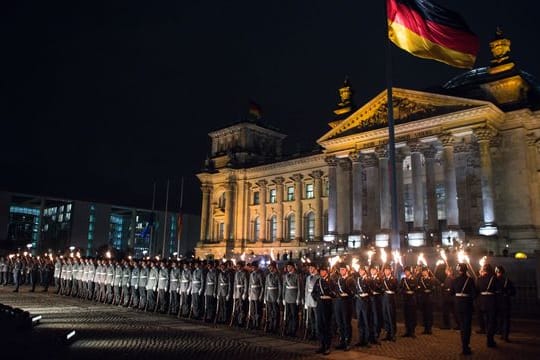 Zahlreiche Soldaten stehen bei einem Großen Zapfenstreich vor dem Reichstagsgebäude in Berlin.