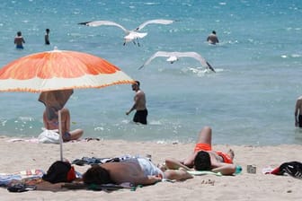 Touristen genießen die Sonne am Strand von Arenal.