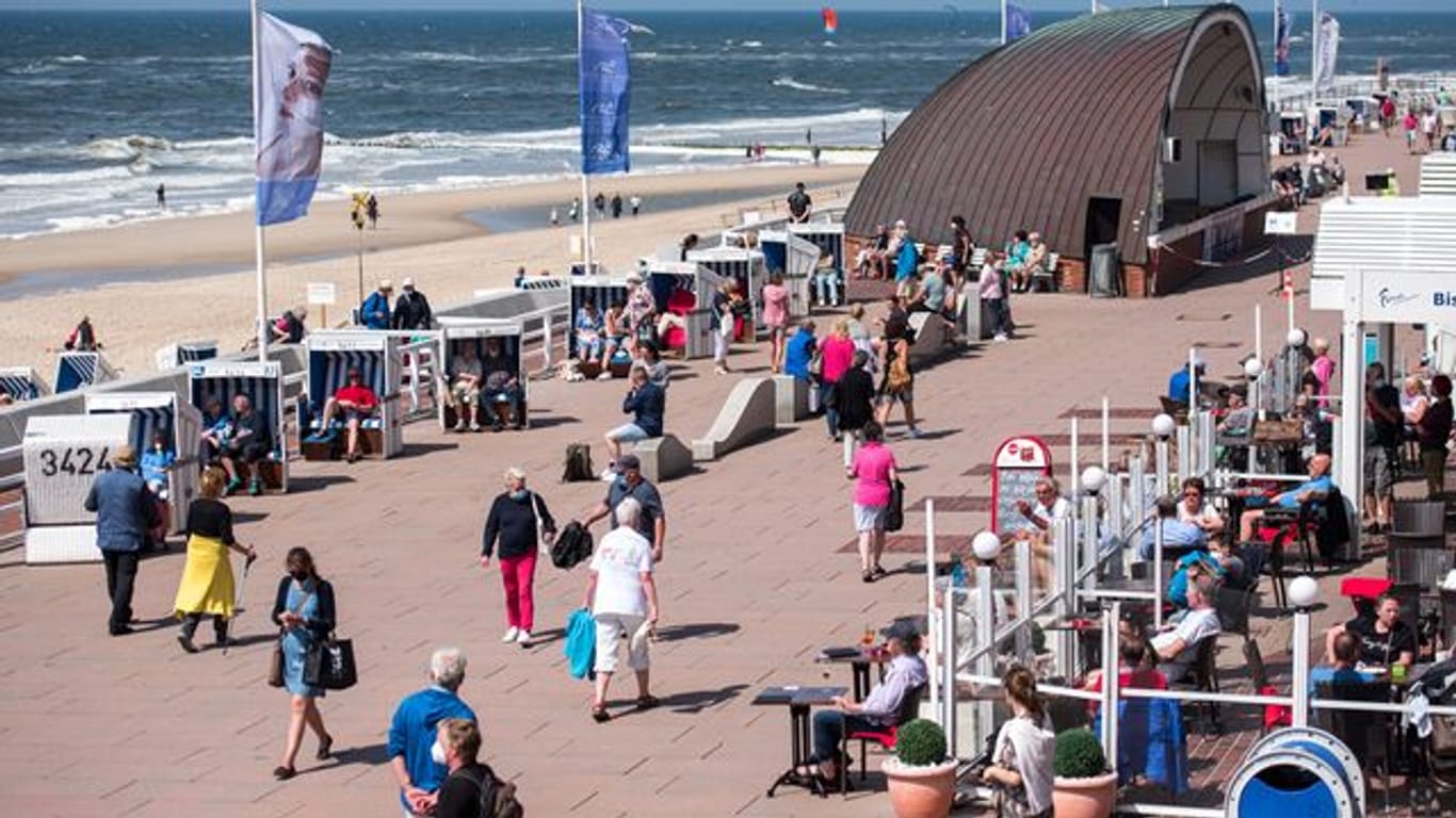 Passanten sind auf der Nordseeinsel Sylt am Strand in Westerland auf der Promenade unterwegs.