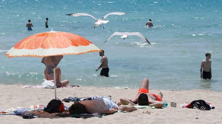 Touristen genießen die Sonne am Strand von Arenal.