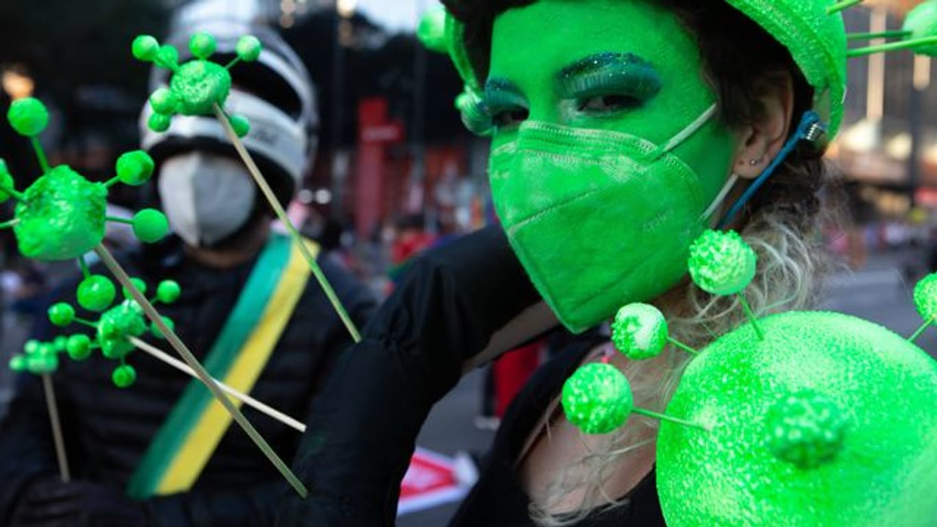 Ein Demonstrantin hat sich ihr Gesicht grün geschminkt und trägt eine grüne Schutzmaske.