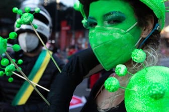 Ein Demonstrantin hat sich ihr Gesicht grün geschminkt und trägt eine grüne Schutzmaske.