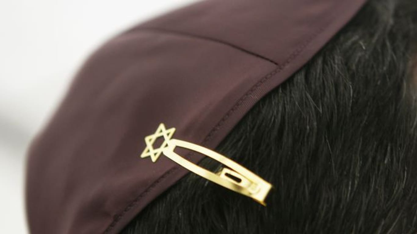 Ein Jude hat sich bei den Feierlichkeiten einer Grundsteinlegung für eine Synagoge seine Kopfbedeckung (Kippa) mit einer Davidstern-Klammer am Haar befestigt.