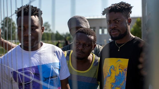 Migranten aus Kamerun stehen am Zaun eines Flüchtlingslagers in Litauen.