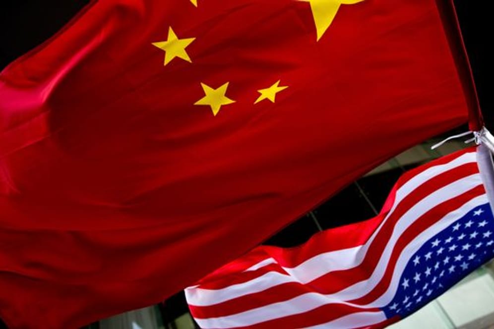 Eine us-amerikanische (unten) und eine chinesische Nationalflagge wehen vor einem Hotel in Peking.