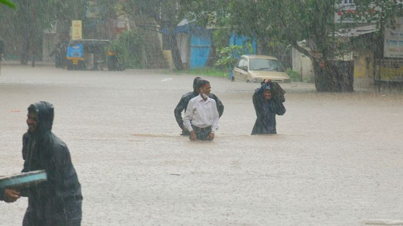Menschen waten in Kolhapur durch das Hochwasser.