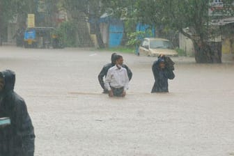 Menschen waten in Kolhapur durch das Hochwasser.