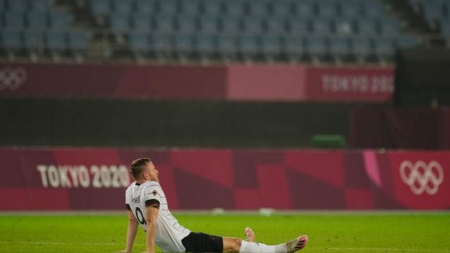 Cedric Teuchert sitzt nach dem Ausscheiden enttäuscht auf dem Rasen.