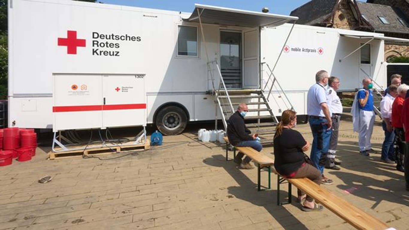 Menschen warten vor einer mobilen Arztpraxis des Deutschen Roten Kreuzes in Bad Neuenahr-Ahrweiler.