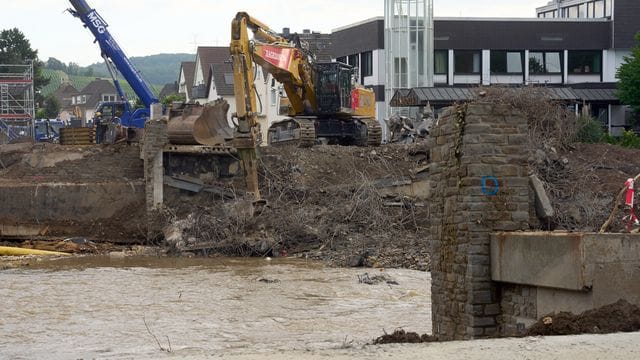 Hilfskräfte reißen eine durch die Flut total zerstörte Brücke über der Ahr ab.