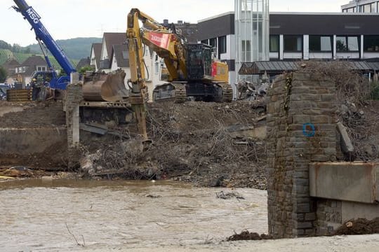 Hilfskräfte reißen eine durch die Flut total zerstörte Brücke über der Ahr ab.