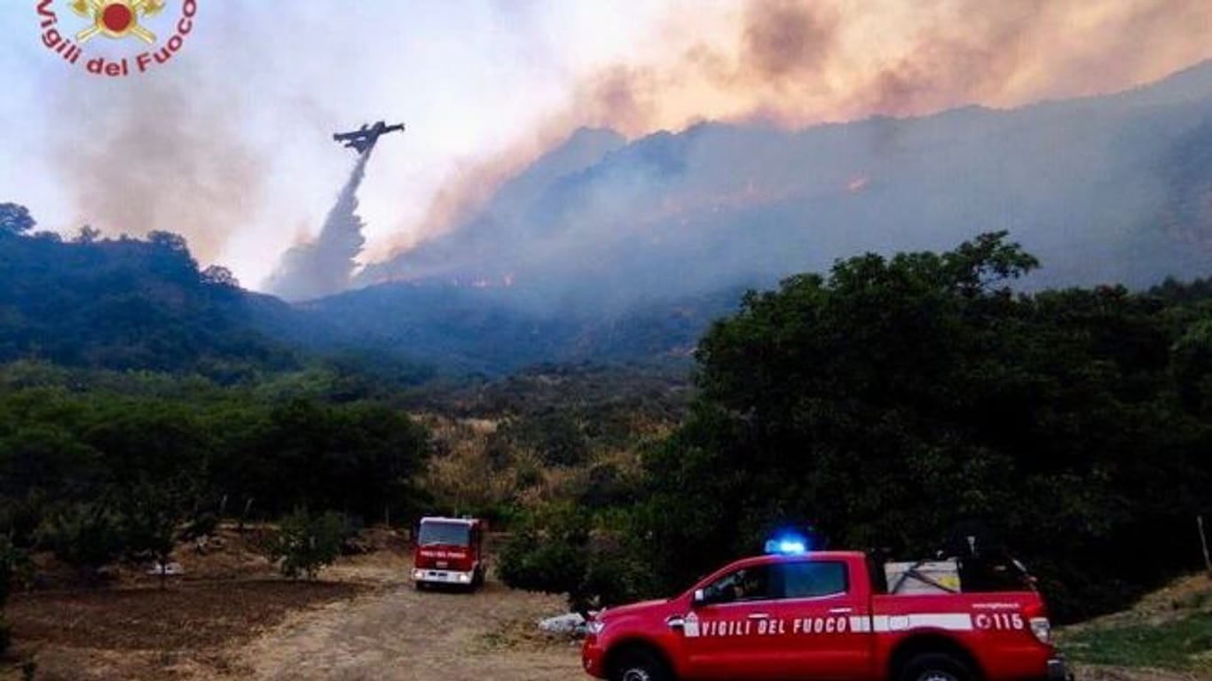 Einsatzkräfte der Feuerwehr kämpfen in der Region Palermo gegen Waldbrände.