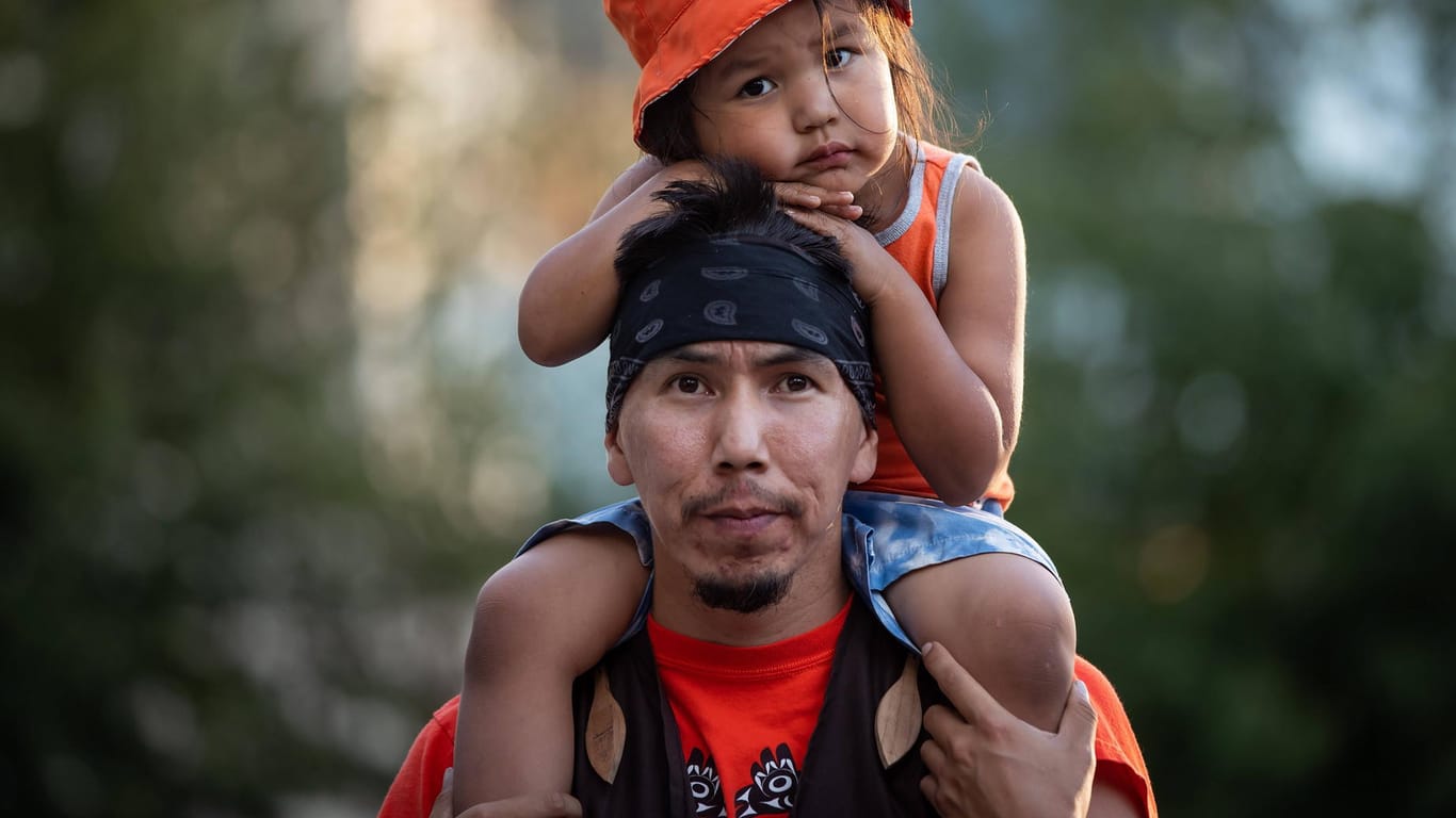 In Vancouver nimmt ein Angehöriger einer indigenen Gruppe mit seinem Sohn an einer Mahnwache teil: Bei der ehemaligen "Kamloops Indian Residential School" wurden dieses Jahr die Überreste von 215 Kindern gefunden.