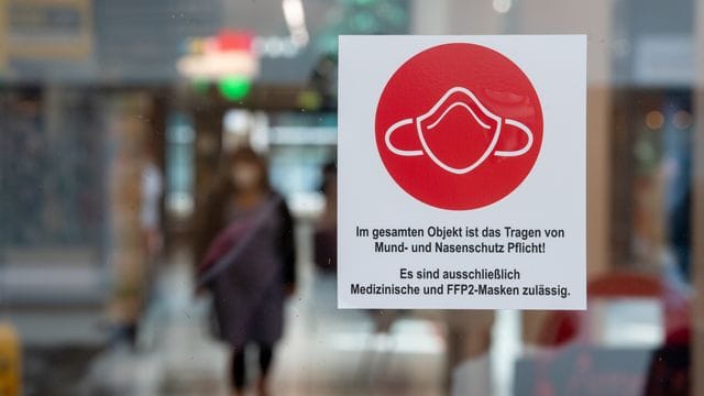 Ein Schild am Eingang zu einer Einkaufspassage weist auf das Tragen von Mund- und Nasenschutz hin. Ein Schild am Eingang zu einer Einkaufspassage weist auf das Tragen von Mund- und Nasenschutz hin.