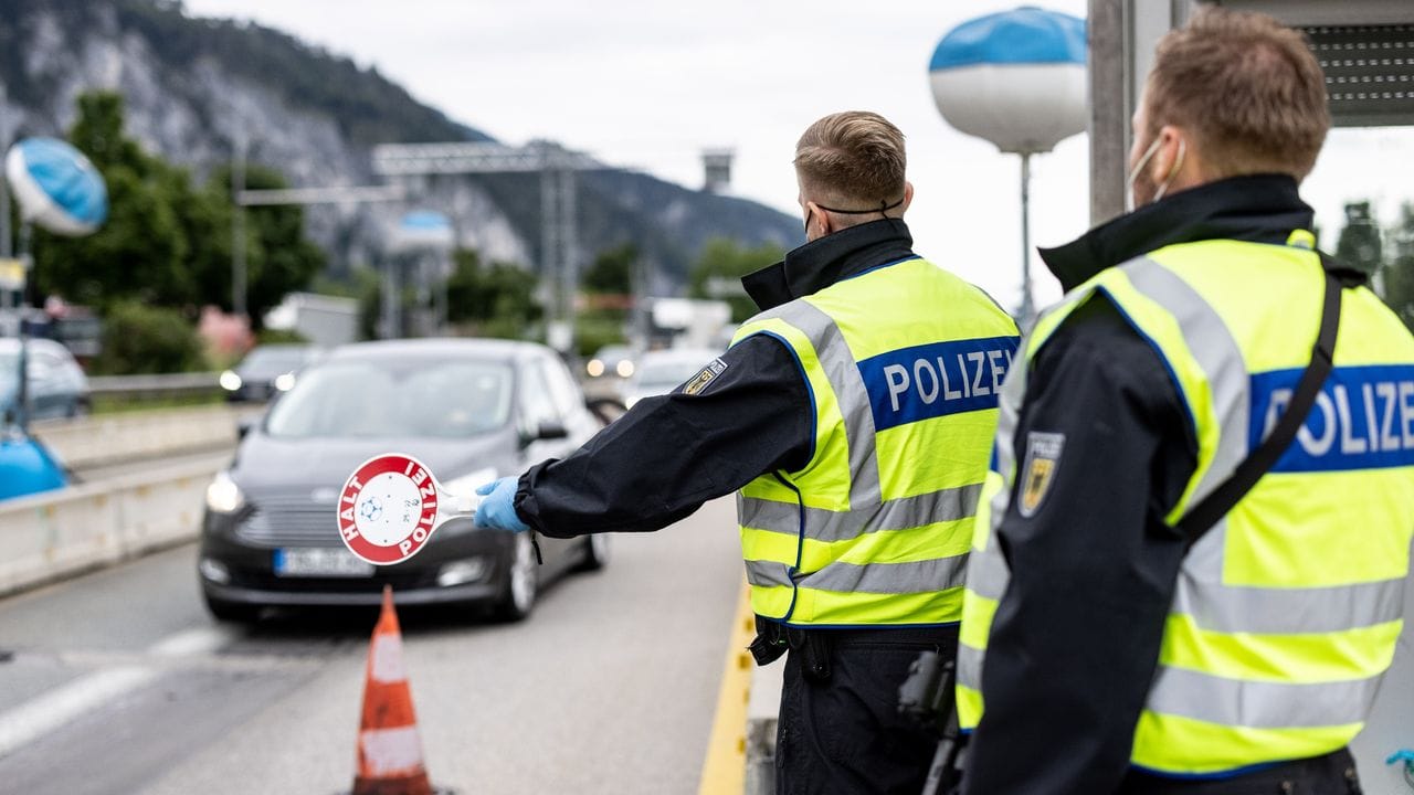 Deutsche Bundespolizisten beobachten an der Grenze zu Österreich auf der Autobahn A93 den Verkehr.