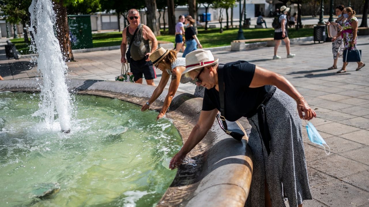 Menschen erfrischen sich bei Temperaturen über 40 Grad mit Wasser aus einem Brunnen auf dem Syntagma-Platz in Athen. Menschen erfrischen sich bei Temperaturen über 40 Grad mit Wasser aus einem Brunnen auf dem Syntagma-Platz in Athen.