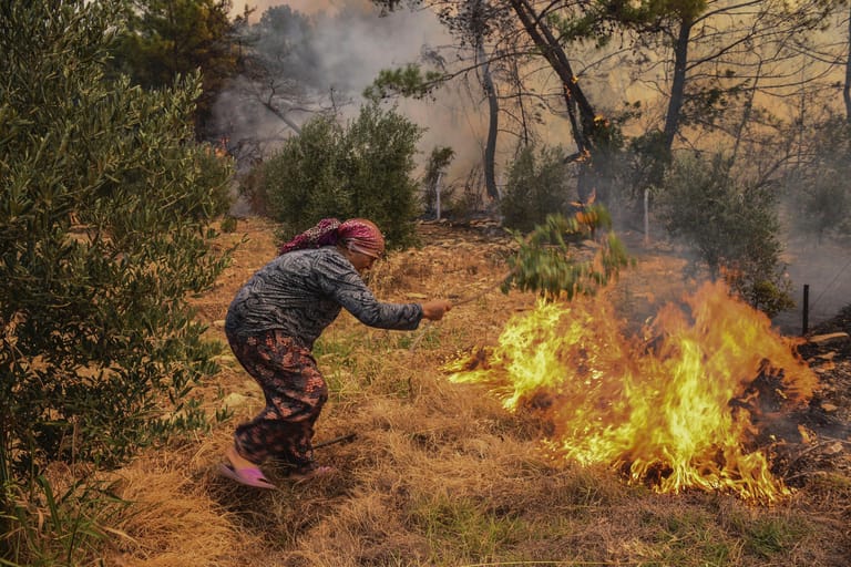 In Manavgat in der südtürkischen Provinz Antalya versucht eine Frau, ein Feuer mit einem Zweig auszuschlagen. Bisher sind in der Türkei acht Menschen durch die Feuer getötet worden. Die Europäische Union schickt derweil Unterstützung: Drei Löschflugzeuge seien mobilisiert worden.