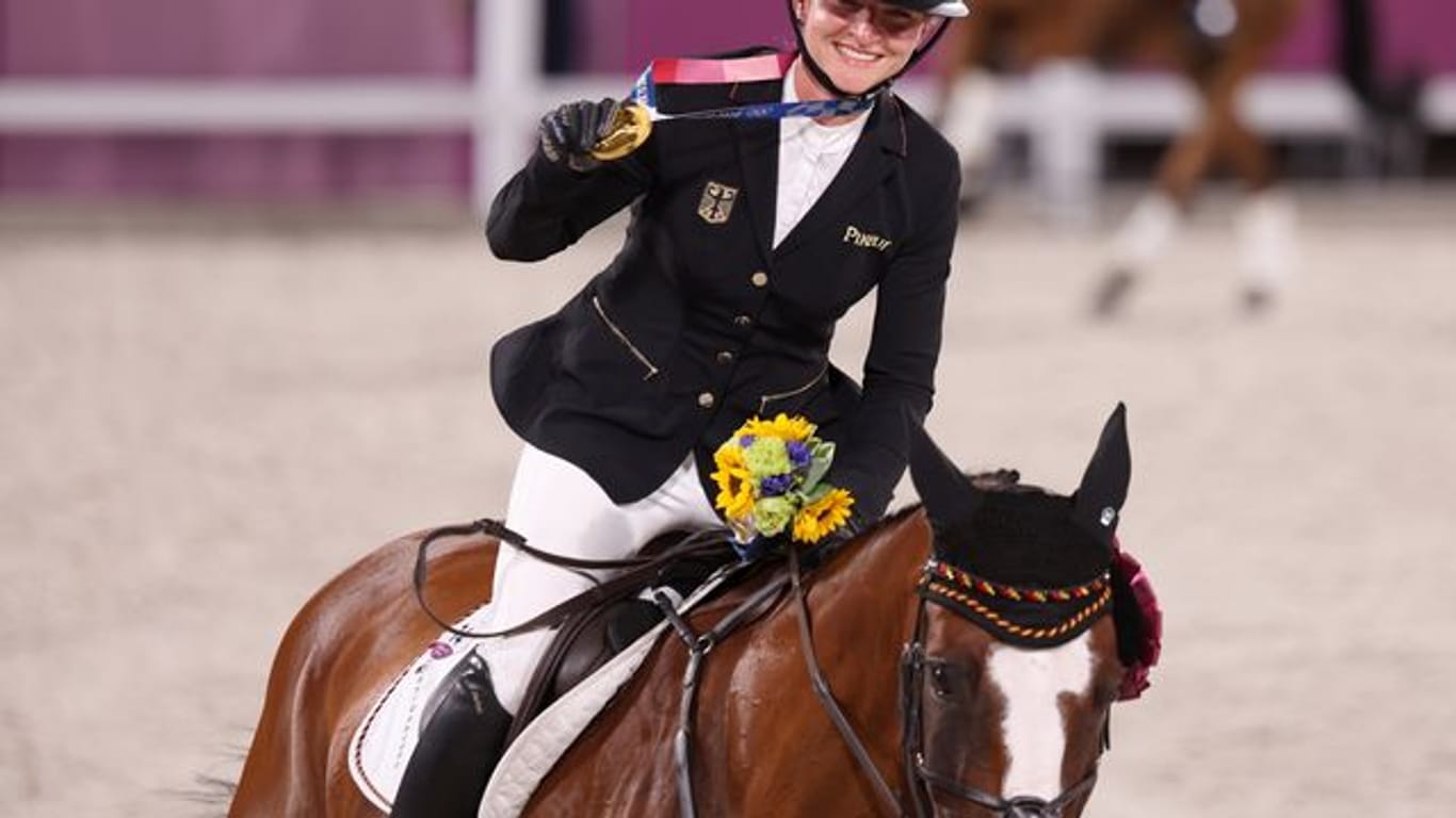 Mit der Goldmedaille um den Hals reitet Julia Krajewski nach der Siegerehrung auf Amande de B`Neville eine Ehrenrunde.
