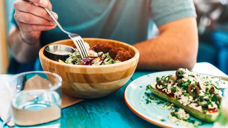 Ein Mann isst Salat: Ob sich Fibromyalgie mithilfe einer speziellen Ernährung bessern kann, bleibt fraglich.
